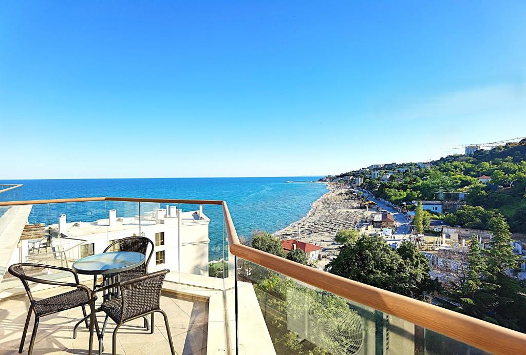 a balcony with two chairs and a view of the ocean at Cabacum Pleasure Beachfront Apartments in Varna City