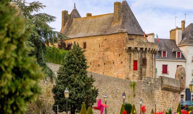 a large brick building with red windows and a tree at Maison centre Hennebont in Hennebont