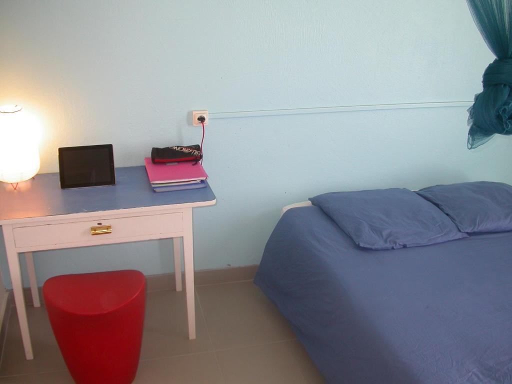 une chambre avec un bureau avec un lit et une table avec un ordinateur portable dans l'établissement Maison de Vacances à St Anne Martinique, à Sainte-Anne