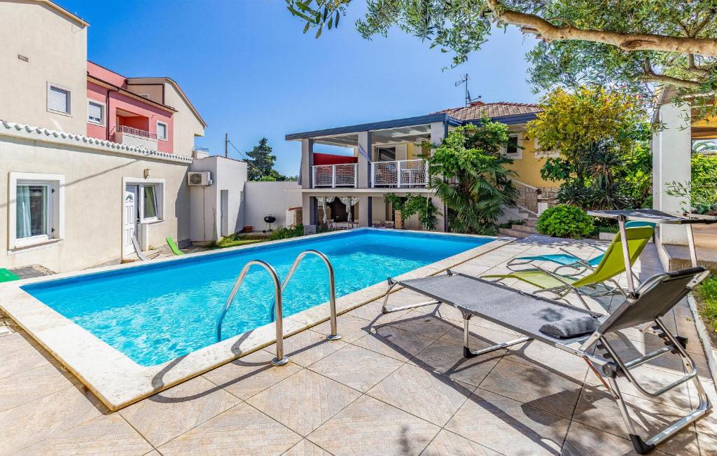 a swimming pool with two chairs and a house at Gorgeous Home In Premantura With Sauna in Premantura