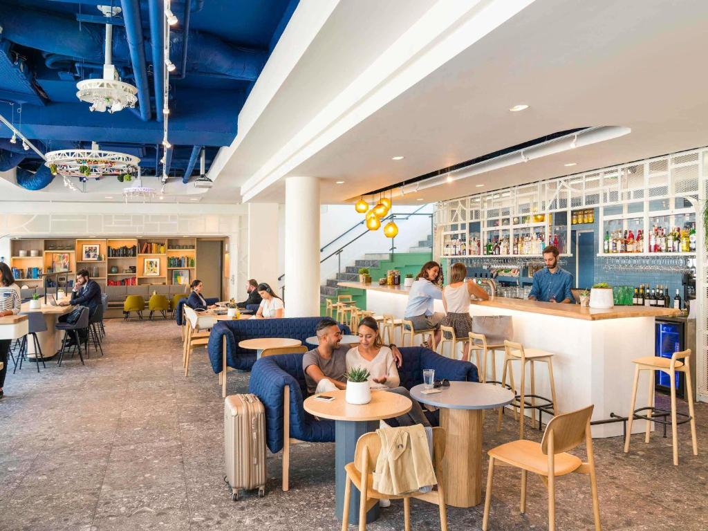 a restaurant with people sitting at tables and a bar at Novotel Paris Centre Gare Montparnasse in Paris