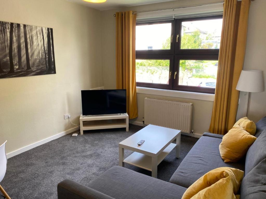 a living room with a couch and a tv at Glen Mhor - Beautiful two bedroom apartment Dunfermline in Townhill