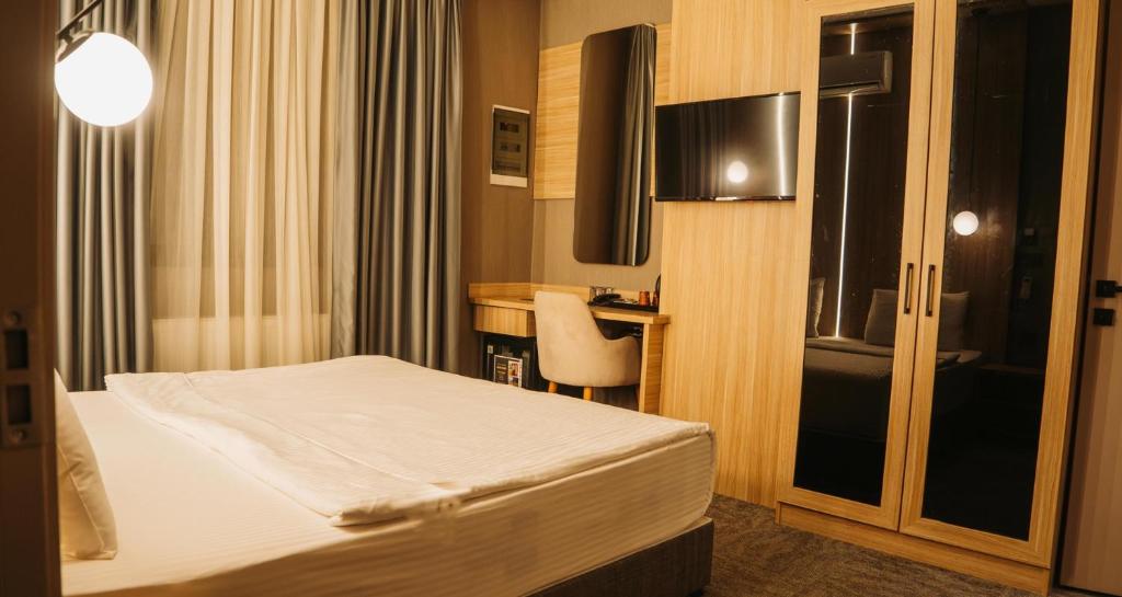 una habitación de hotel con una cama y un escritorio en Royal Mass Airport Business Hotel, en Arnavutköy