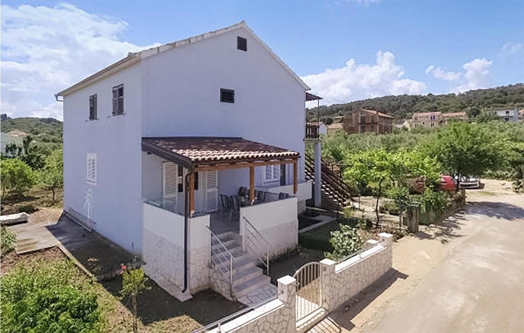 a white house with a porch and a fence at 2 Bedroom Nice Apartment In Pasman in Pašman