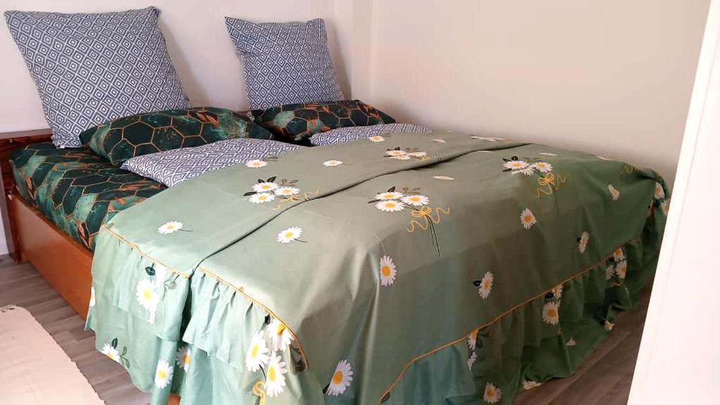 a bed with a green comforter with flowers on it at White Sand Haven Guest House in Ebhausen