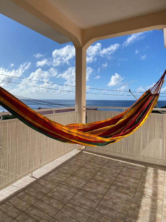 a hammock on a balcony with a view of the ocean at Les Alizés 3 chambres et piscine Les Anses d Arlet in Les Anses-dʼArlets