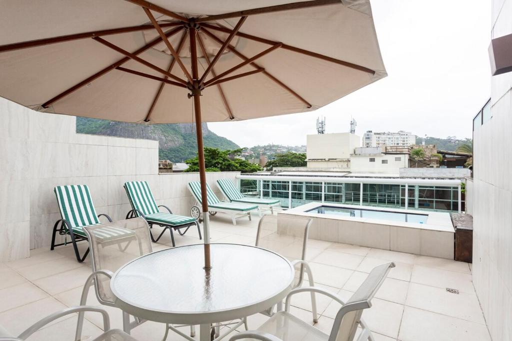 a patio with a table and chairs and an umbrella at Cobertura com linda vista da praia do Pêpe in Búzios