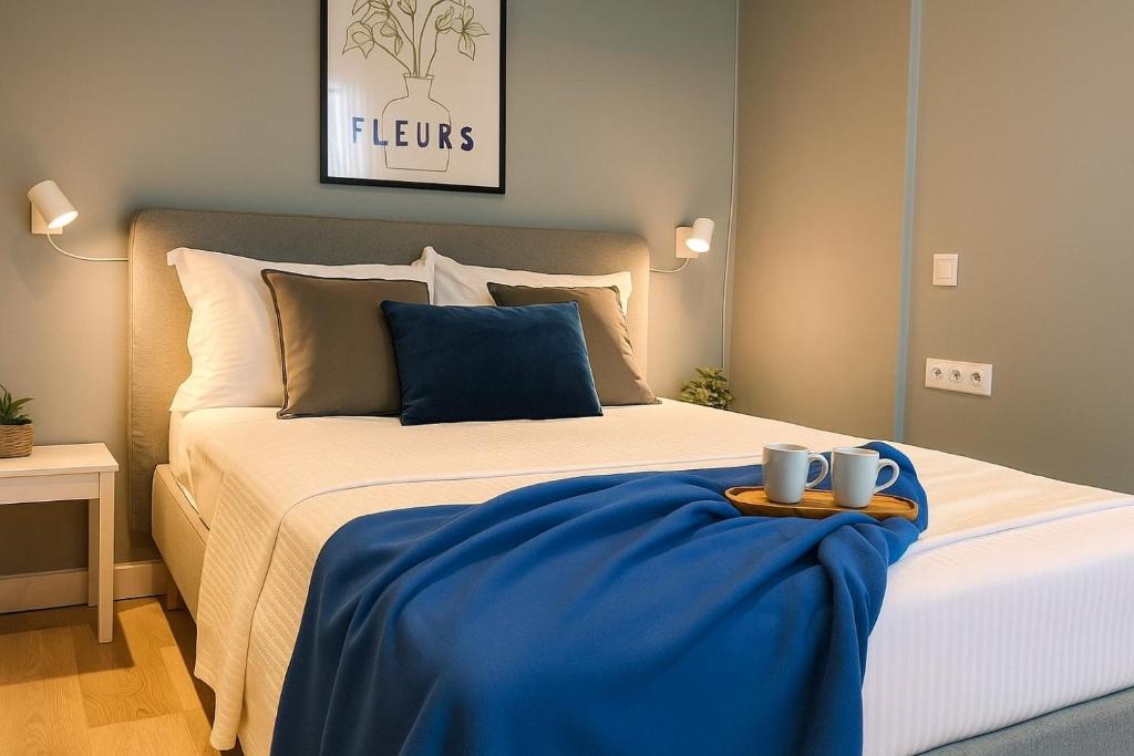 a bed with a blue blanket and two mugs on it at Andreas and Nelly in Thessaloniki
