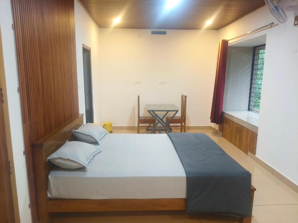 a bedroom with a bed and a table in a room at Wayanad Home stay in Kaniyāmbetta