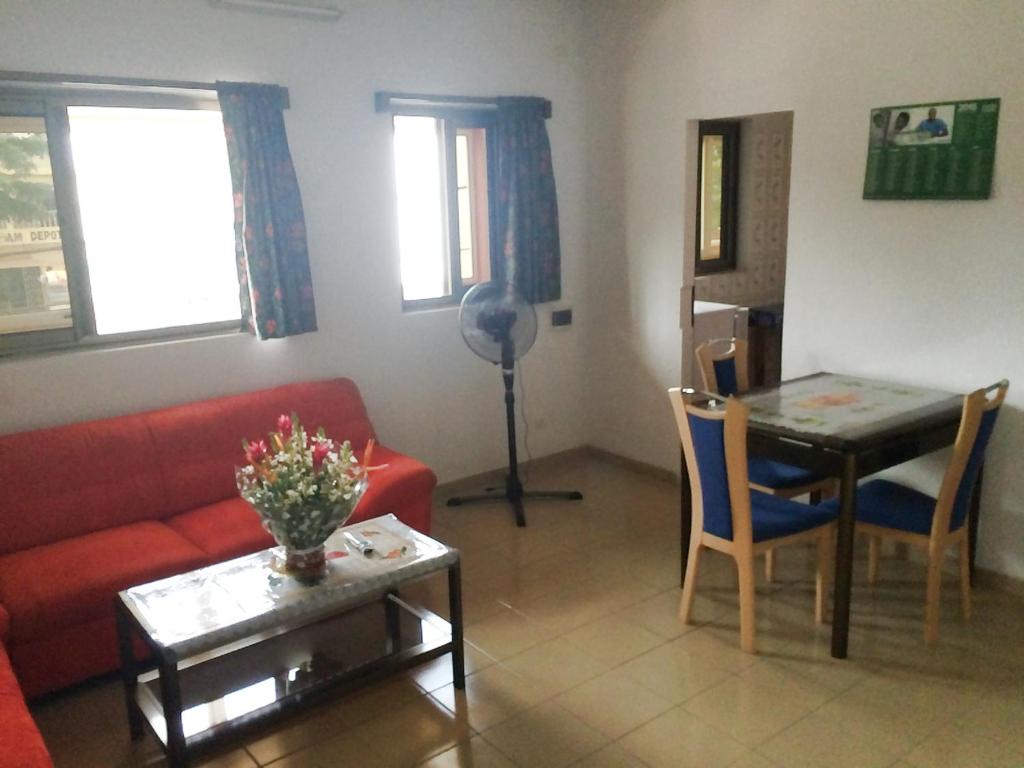 a living room with a red couch and a table at Appartements Lome Marie Antoinette in Atigan