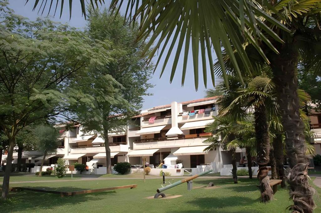 un edificio con un parque infantil delante de él en Houses and Apts. in Lignano 21694, en Lignano Sabbiadoro