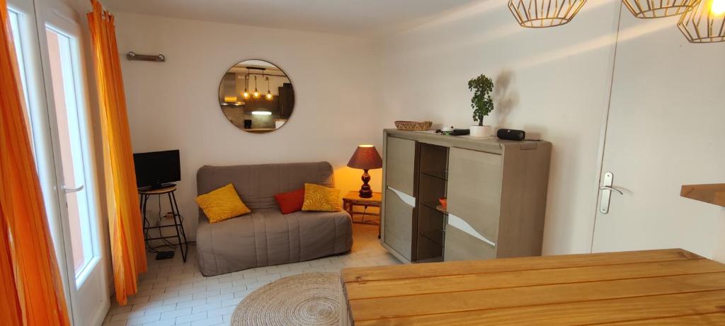 un soggiorno con un divano e uno specchio di Appartement terrasse dans une résidence calme a Cap d'Agde