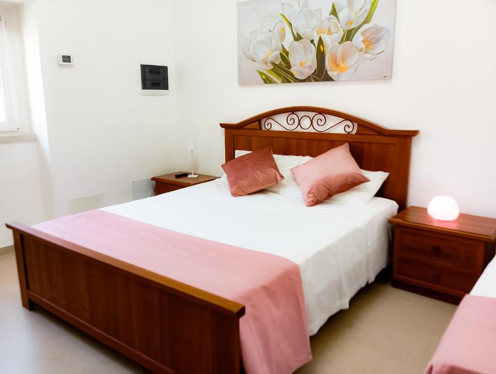a bedroom with a bed with white sheets and pink pillows at La Fontana in Montalbano