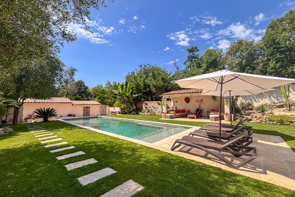 une piscine avec deux chaises et un parasol dans l'établissement Dolce Apartment 3 Bedrooms 5 Guests 10min to Cannes, à Mandelieu-la-Napoule