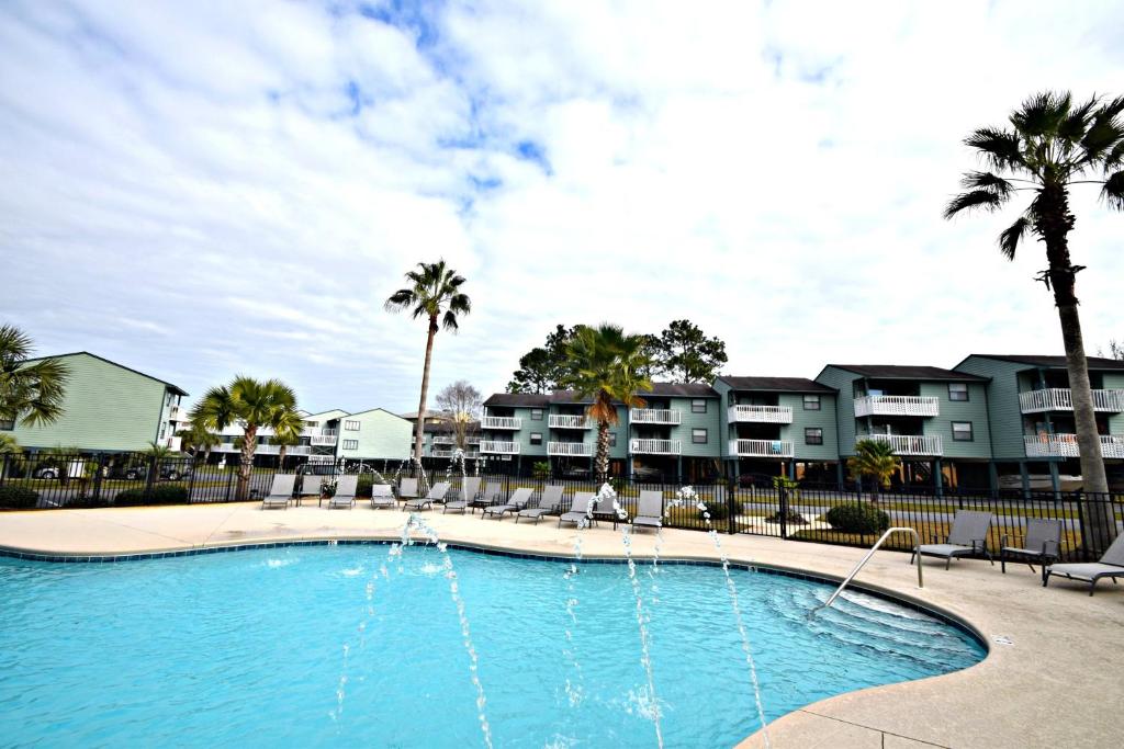 ein großer Swimmingpool mit Palmen und Gebäuden in der Unterkunft Bayview in Orange Beach