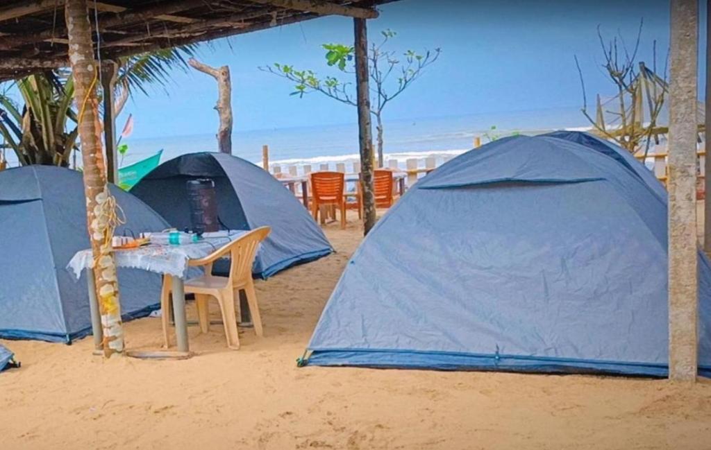 Tres carpas en la playa con mesa y sillas. en S R A vill, en Gokarna