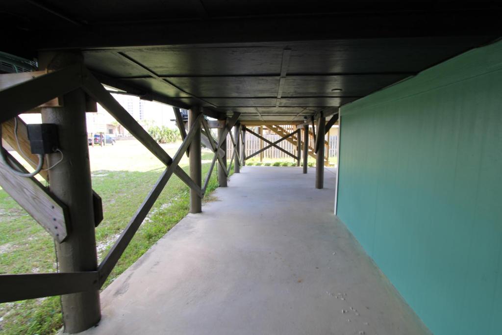 een lange loopbrug onder een gebouw met een groene muur bij Silver Sands North in Gulf Shores