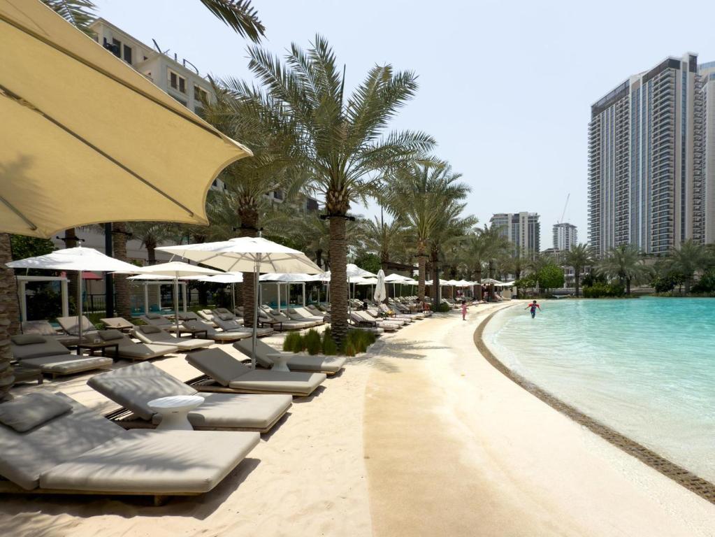a beach with lounge chairs and a swimming pool at GuestReady - Lux living with an infinity pool in Dubai