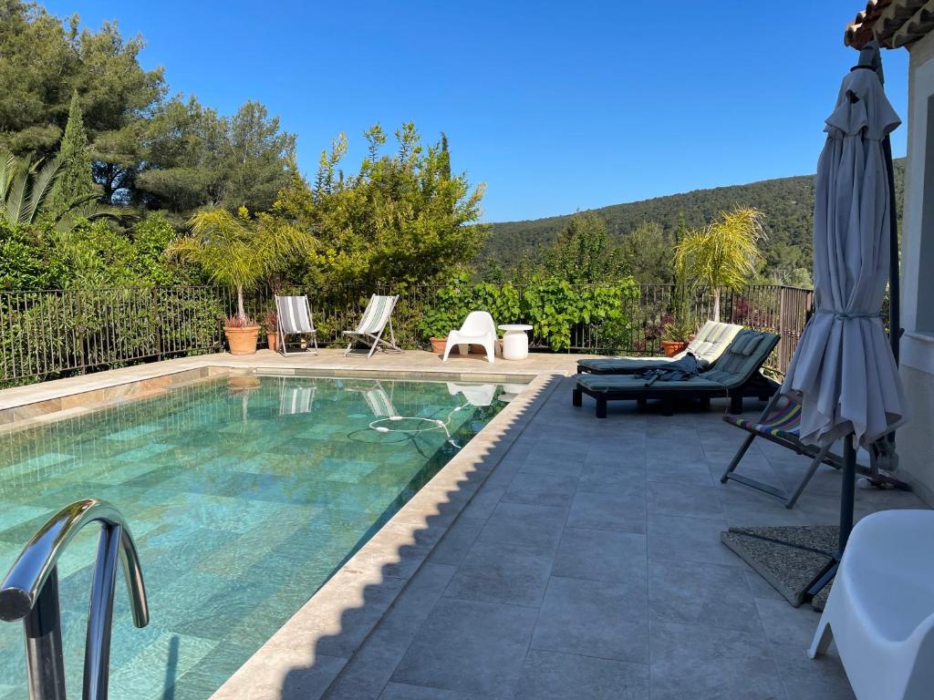 a swimming pool with a patio and an umbrella at Loft dans cadre de verdure in Ceyreste