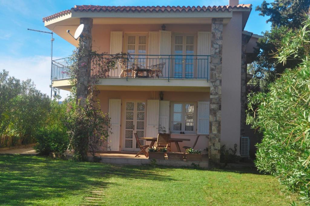 una casa con balcone e tavolo in cortile di Villa Rosa a Budoni