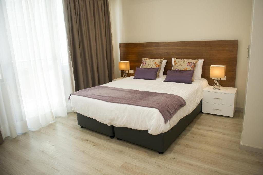 ein Schlafzimmer mit einem großen Bett mit lila Kissen in der Unterkunft Manolia City Residences in Nikosia