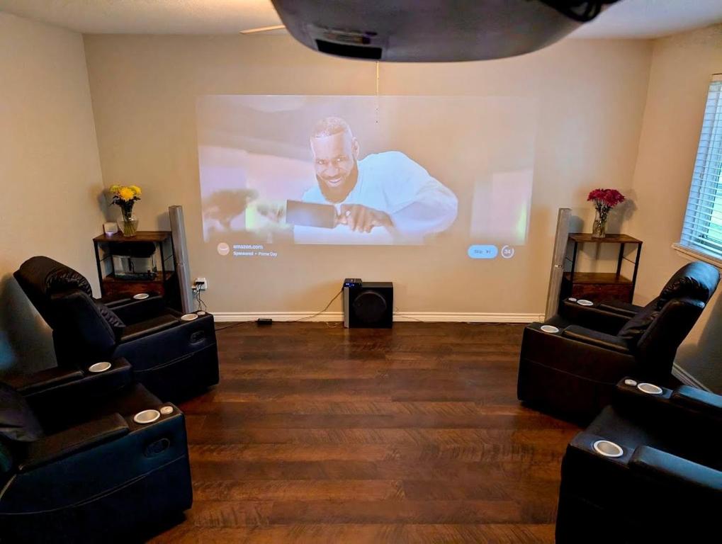 a room with a large screen with a man on a projector at By Popular Demand - Houston in Houston