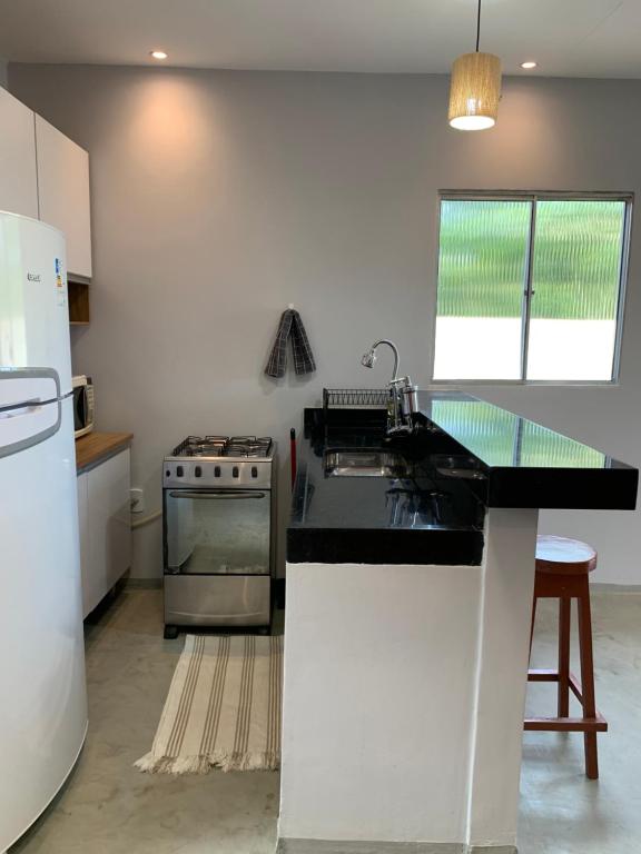 a kitchen with a stove and a sink and a refrigerator at Casa Aconchegante com Piscina in Porto Seguro