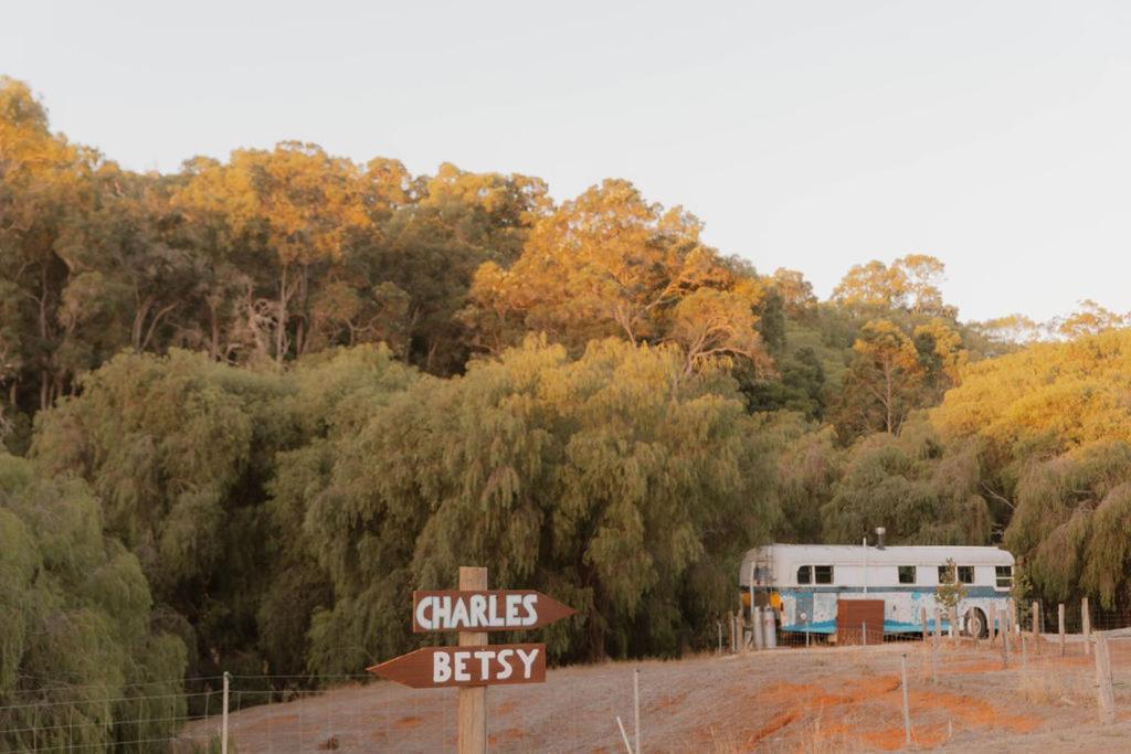 a rv and a sign in front of a forest at R&R Bus Retreat in Wellington Mills