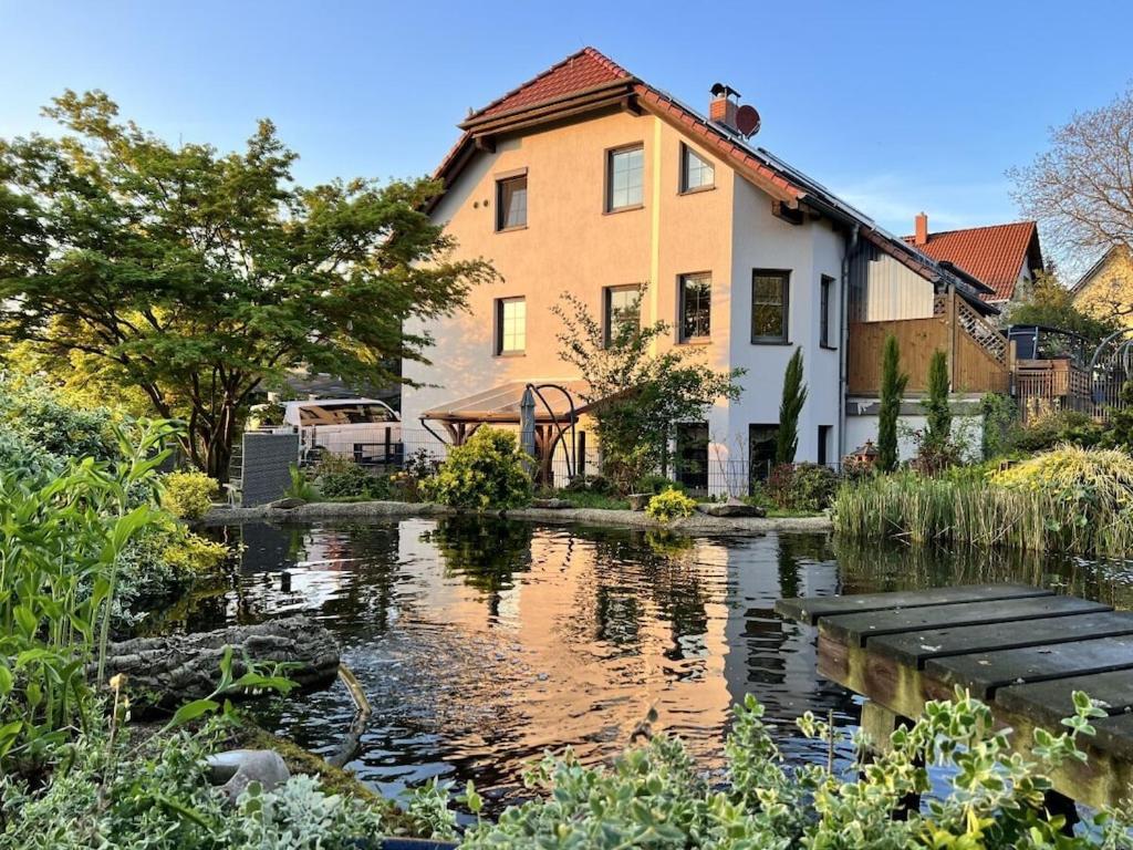 a house and a pond in front of a house at 1-bedroom holiday apartment in Naundorf