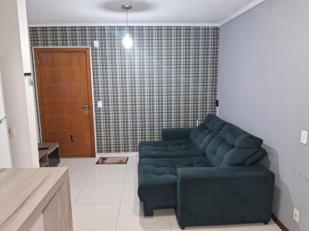 a living room with a blue couch and a brown door at Apartamento próximo ao centro e Havan in Gravataí