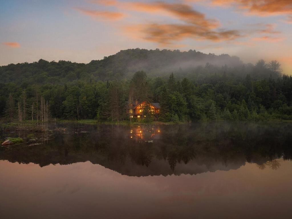 ein Haus am Ufer eines Sees bei Sonnenuntergang in der Unterkunft Chalet Mazama - Private Lake - Hot Tub - 16P in Wentworth-Nord