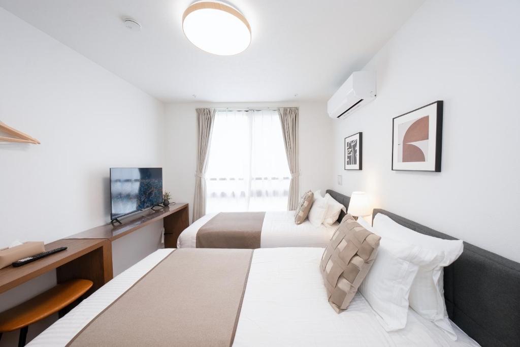 a hotel room with two beds and a television at 銀座線徒歩9分 松が谷アパート in Tokyo