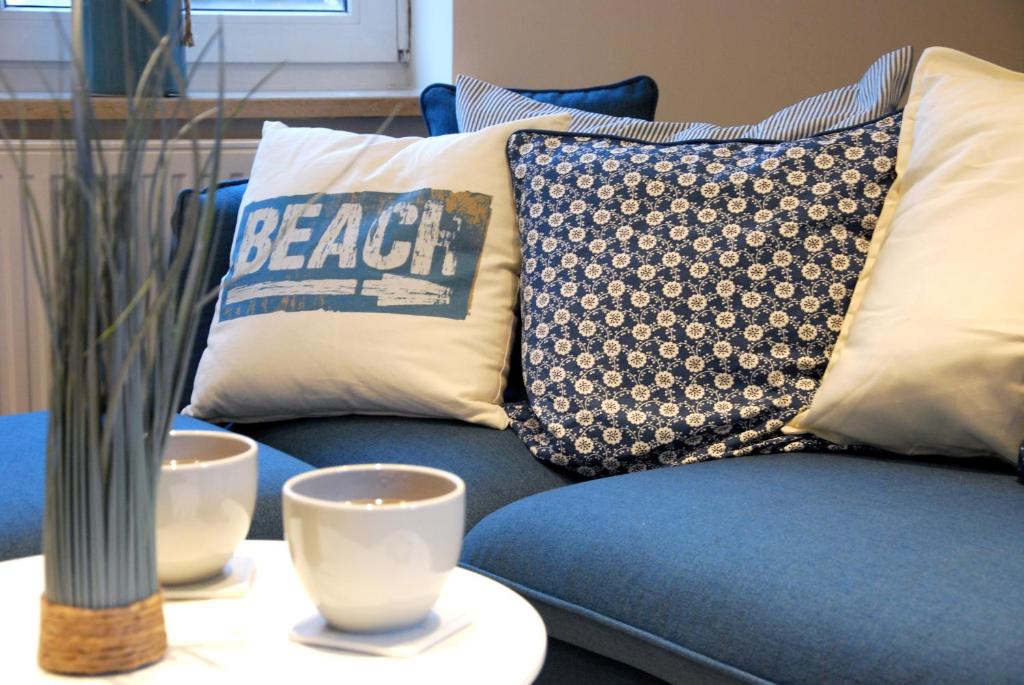 un sofá azul con almohadas y 2 tazas en una mesa en Meine ECKE 1 en Eckernförde