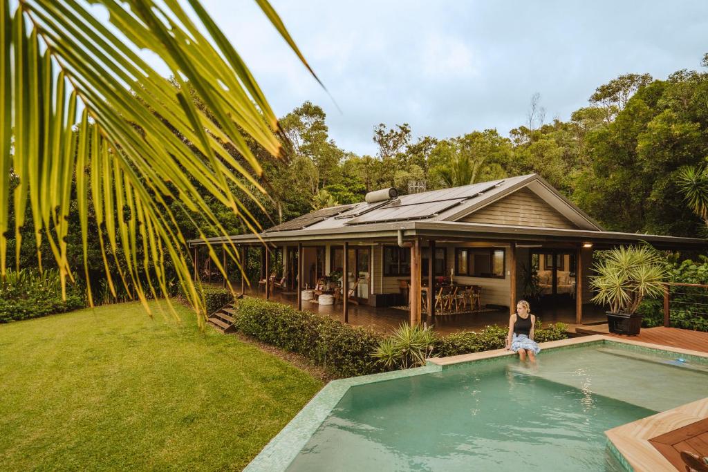 a person standing in a swimming pool next to a house at Port Douglas Alamanda Estate w Ocean Views & Pool in Craiglie