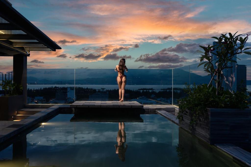 a woman in a bikini standing on the edge of a swimming pool at Rest Hotel & Apartment in Danang
