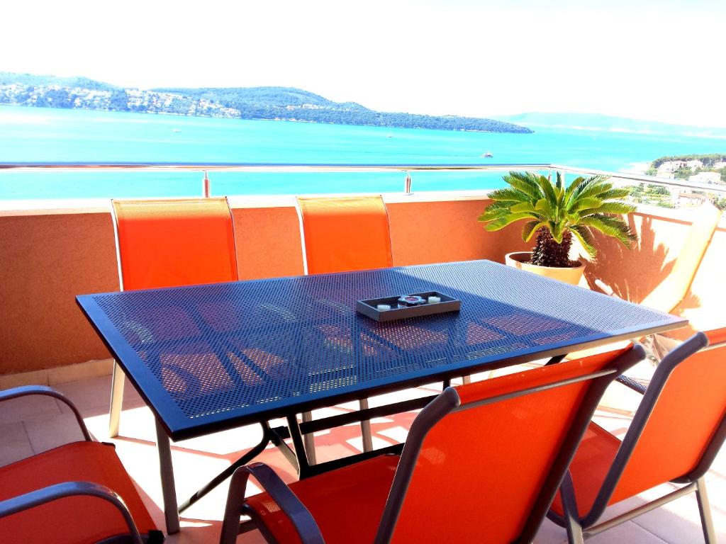 een blauwe tafel en stoelen op een balkon met uitzicht op de oceaan bij Apartment Jurčević in Trogir