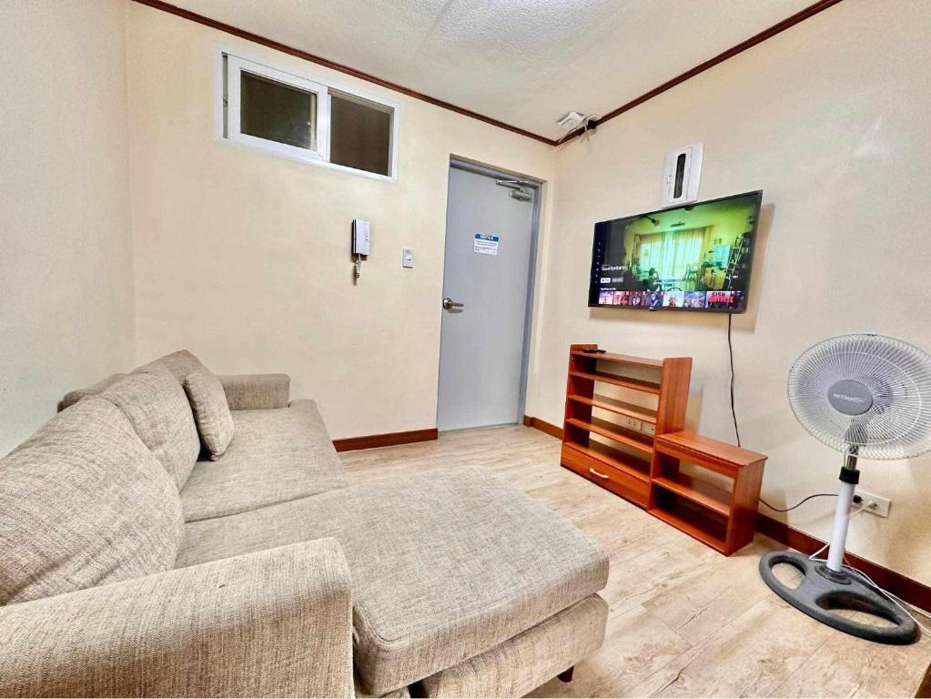 Una sala de estar con un sofá y un televisor de pantalla plana. en Lakbay Philippines, en Baguio