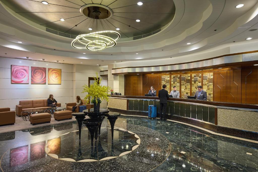 Eine Lobby eines Hotels mit einem Mann, der an einer Bar steht. in der Unterkunft Rosedale Hotel Hong Kong in Hongkong