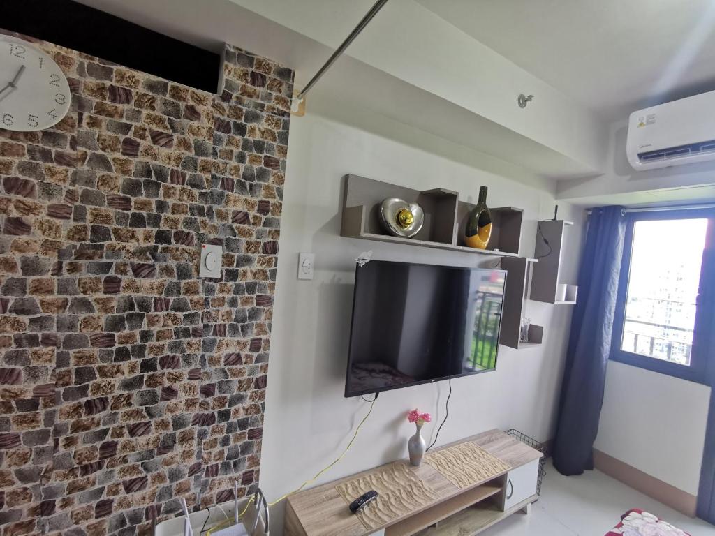 a living room with a tv and a brick wall at Aldo mall of Asia condotel in Manila