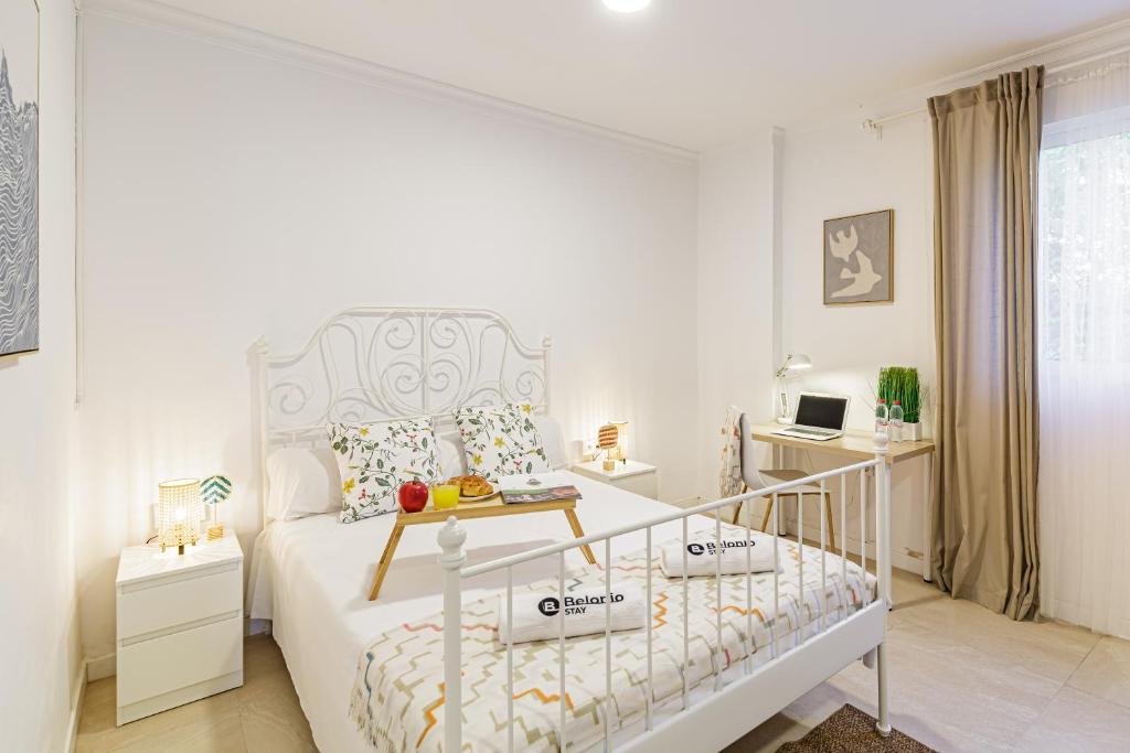 a white bedroom with a bed and a desk at Stay Belonio El Palo Beach in Málaga