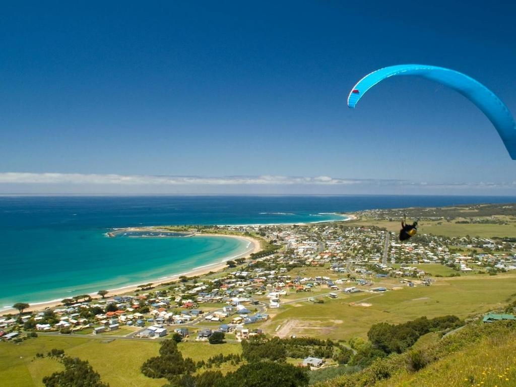 a person is flying a parachute over a beach at 4BR Apollo Bay Beach house in Apollo Bay