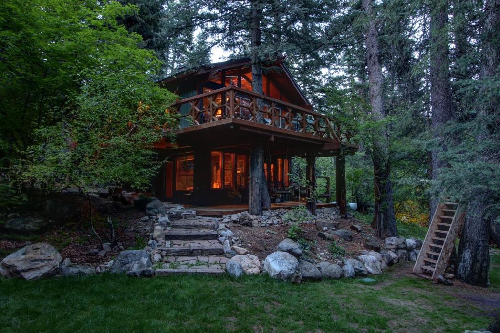 a cabin in the woods with a staircase leading up to it at Treehouse on the Stream in Sundance