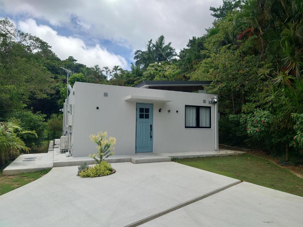 a white house with a blue door at VILLA Esse UNA in Nago