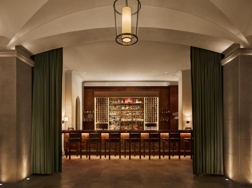a bar in a hotel lobby with green curtains at Refinery Hotel - New York in New York