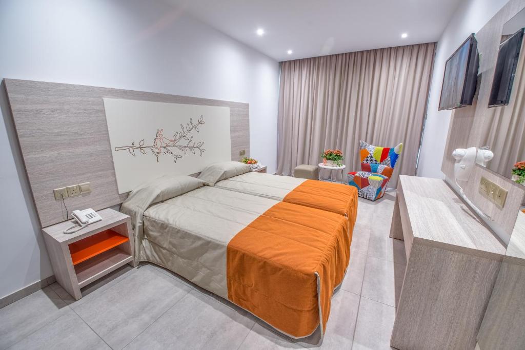 a bedroom with a bed with an orange blanket at Nicholas Color Hotel in Ayia Napa