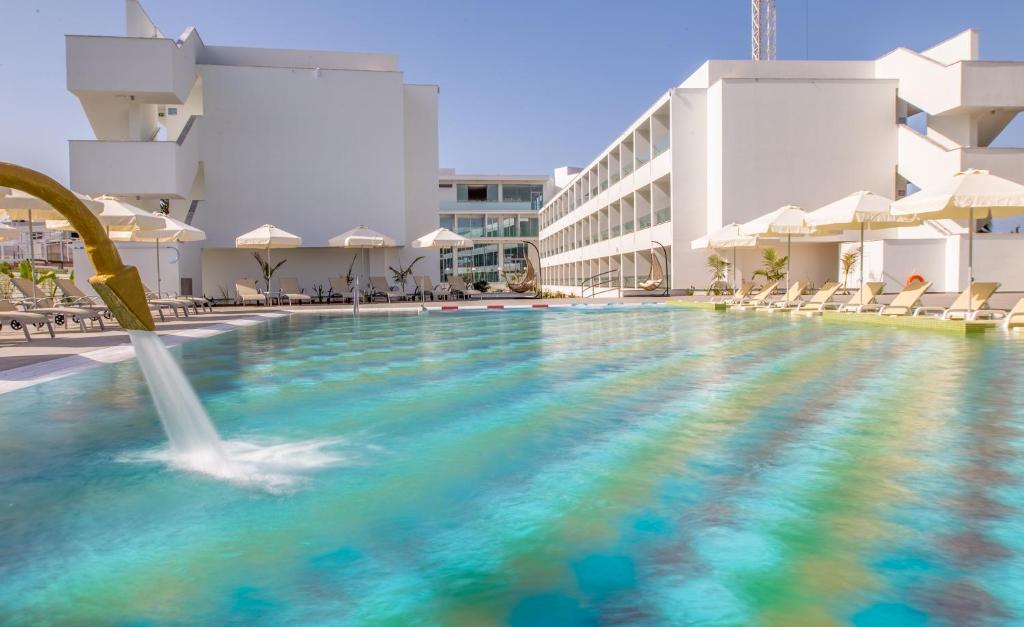 a swimming pool with a fountain in the middle of a building at Nicholas Color Hotel in Ayia Napa