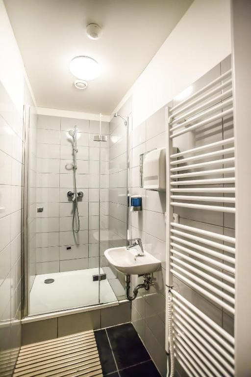 a bathroom with a glass shower and a sink at Ahoy! Hostel in Prague