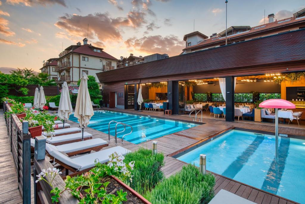 an outdoor pool with lounge chairs and umbrellas at Lucky Bansko Aparthotel SPA & Relax in Bansko