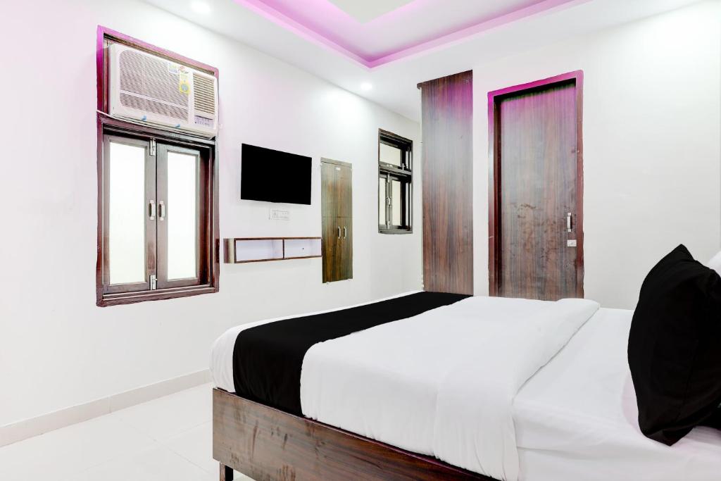 a white bedroom with a bed and a tv at FabHotel DD Green Residency in New Delhi