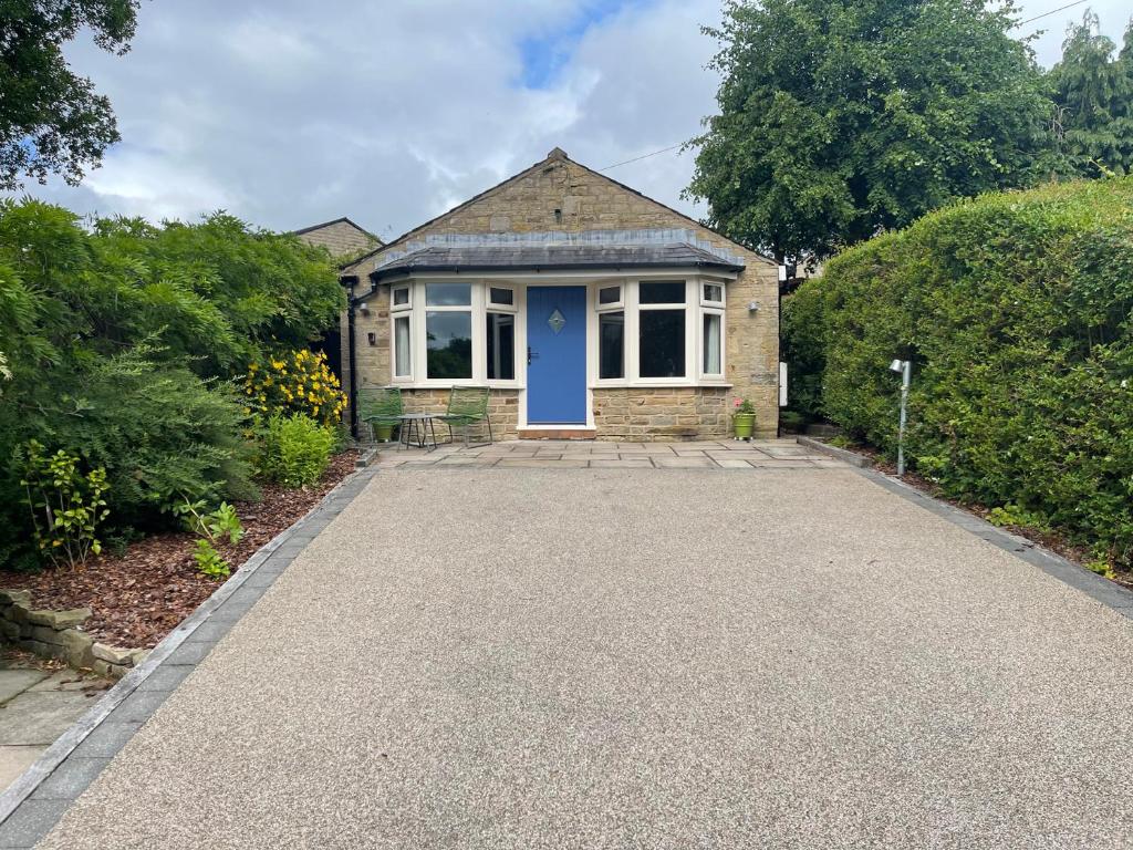 ein Backsteinhaus mit blauer Tür und einer Einfahrt in der Unterkunft Hockerley Cottage in Highpeak Junction